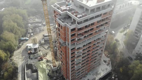 Birds eye view on tower crane in fog standing next to residential building.