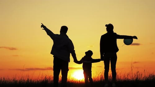 Family Silhouette Holding Hands at Warm Sunset