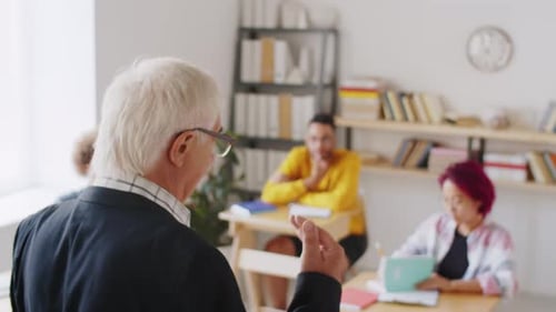 Senior Professor Speaking to College Students in Classroom