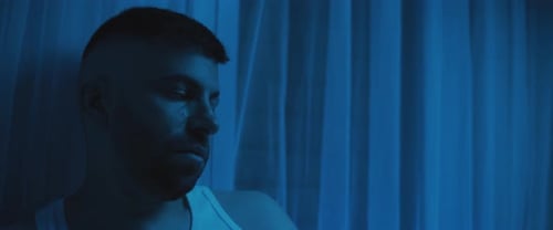 Close up of a depressed man sitting in the bedroom, staring to nowhere