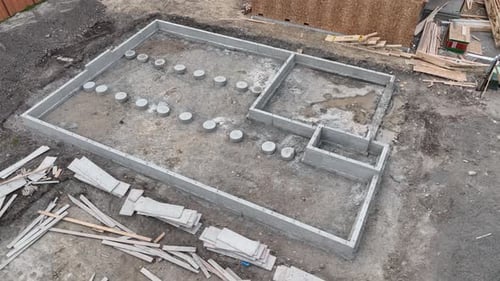 Umlaufende Luftaufnahme einer frischen Baustelle mit einem Betonfundament.