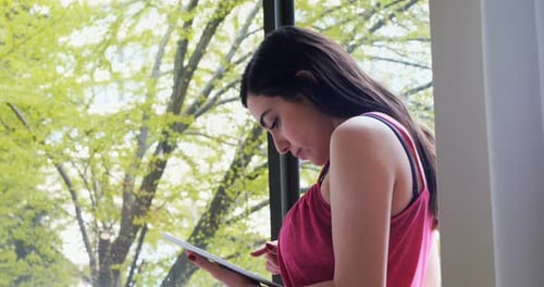 Beautiful woman using digital tablet near window 4k