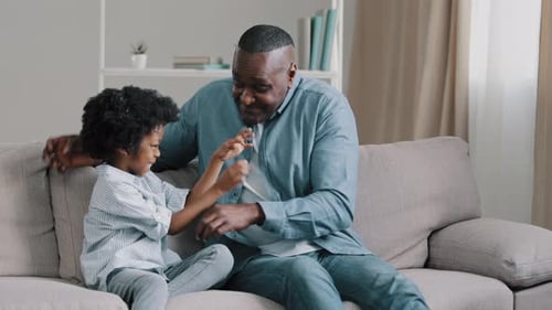 Grandfather and Granddaughter Playfully Interact on Sofa