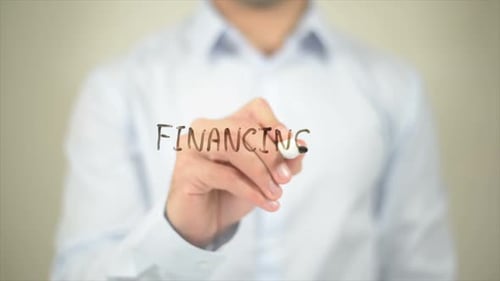 Hand Writes Word Financing on Clear Surface