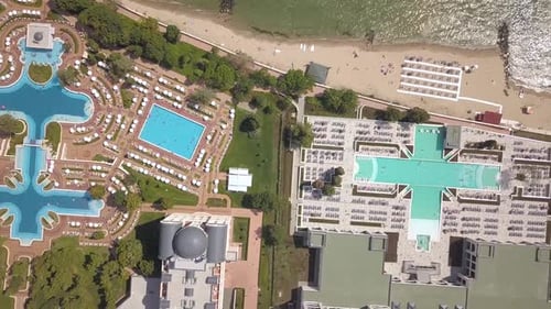 Top down aerial view of hotels on ocean shore with swimming pools with blue water and beach
