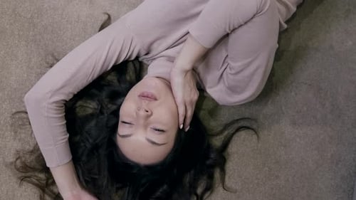 Charming Young Brunette Woman Is Lying on Carpet in Room Top View Portrait in Apartment