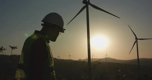 A Young Engineer Inspects the Windmills Hiding His Hand From the Sun