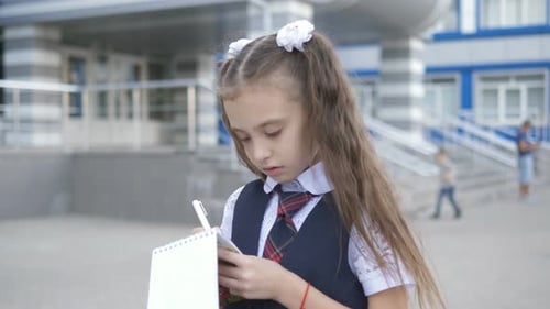 Student-centered Elementary School in School Uniform Writes or Draws Something in a Notebook Near