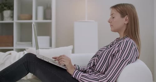 Woman Using Laptop on Couch at Home