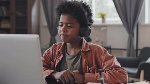 Boy Wearing Headphones Uses Laptop at Home