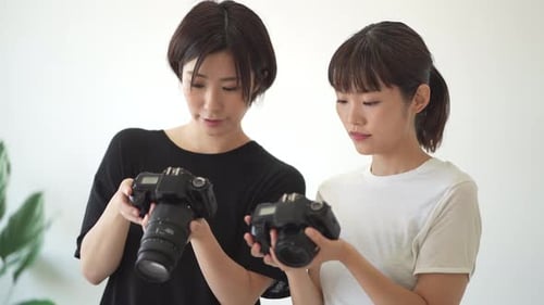 Young Women Discussing Digital Cameras Indoors