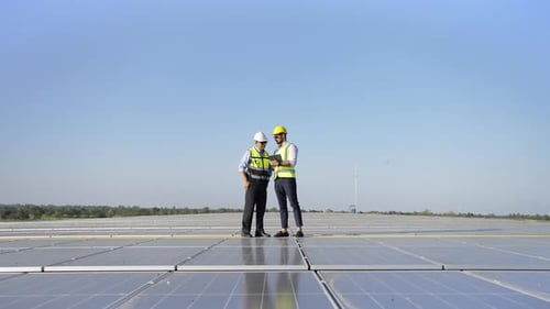4K Professional engineer using tablet maintaining solar cell panels together on building rooftop.