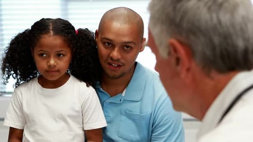 Doctor Talks with Child and Father in Clinic