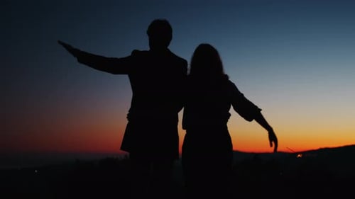 Couple Silhouetted Against Colorful Mountain Sunset
