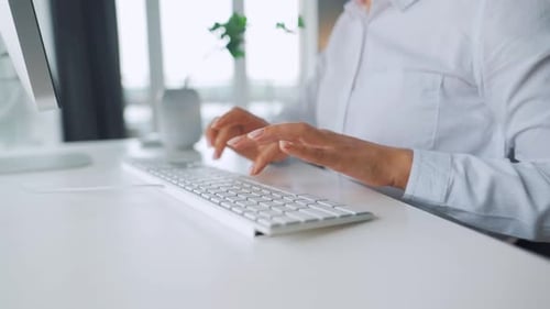 Woman Typing on Keyboard in Bright Office