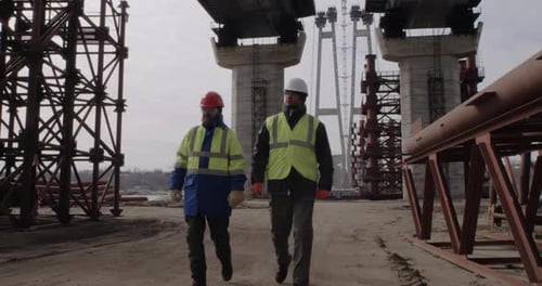 Des constructeurs masculins marchant sous un pont