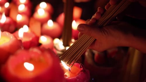 Hand Lighting Incense Sticks from Glowing Candles