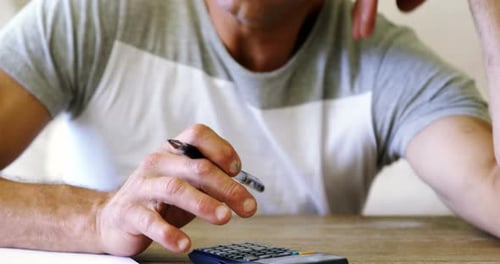 Tense man using calculator in living room