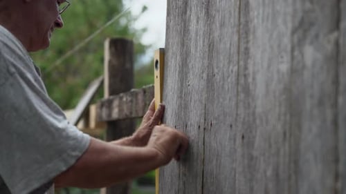 Senior Adult Hammering Nails into a Wooden Barn Wall