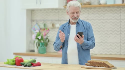 Senior Man Video Calling on Smartphone in Kitchen