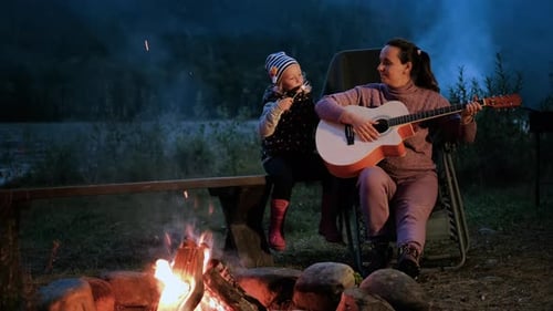 Mother and Daughter Camping with Guitar By River