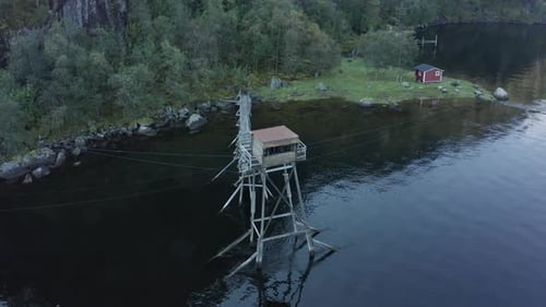 Toma aérea sobre la vieja cabaña de pesca de salmón en medio del lago - Laksegilje, Noruega