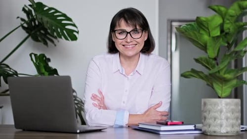 Smiling Woman Sitting at Desk with Laptop