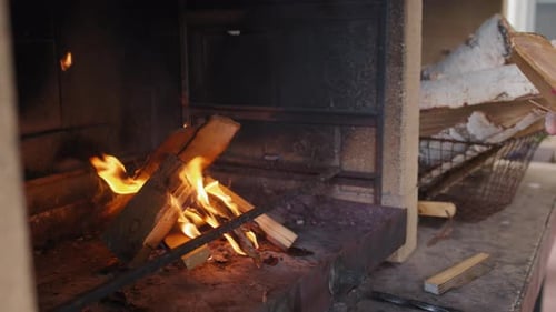 Person Adds Firewood to Warm Rustic Fireplace