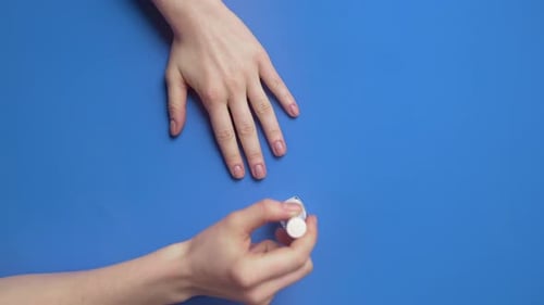 Woman Paints Her Nails with Transparent Protective Nail Polish on the Background, Nail Care and