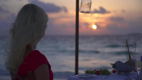 A man and woman couple eat dinner and dine on a tropical island beach.