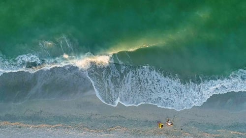 Dos personas caminan por la playa de arena. Vista aérea