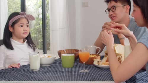 Family Laughing and Eating Breakfast Together at Home
