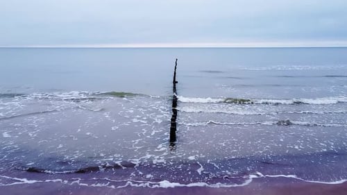 Beautiful aerial view of an old wooden pier at the Baltic sea coastline, overcast day, white sand be