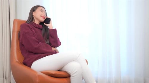 Woman in Sweater Sits and Talks on Phone