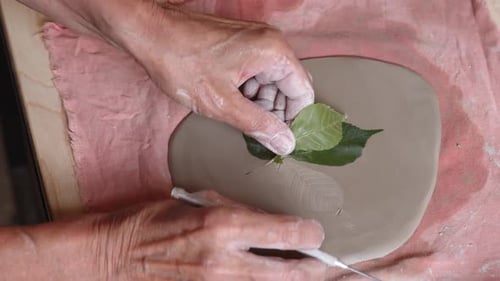 Potter Hands Décorer un morceau d'argile utilisant