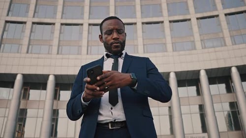 Man Checks Watch While Using Smartphone in City