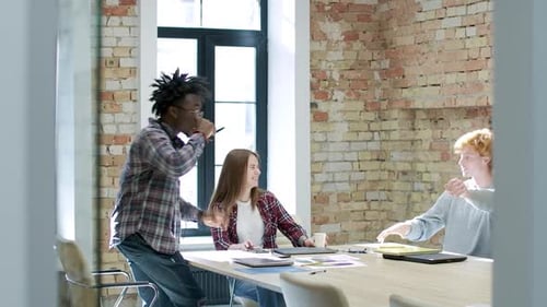Wide Shot, Business Meeting of Cheerful Millennial Multiethnic Colleagues in Sunny Office. Positive