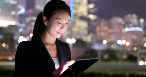 Woman Uses Tablet in Urban Night Environment