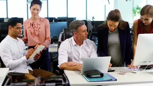 Executives interacting with each other at desk in office