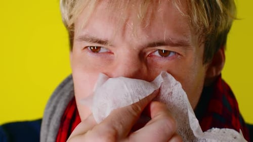 Young Adult Wipes Runny Nose with Tissue