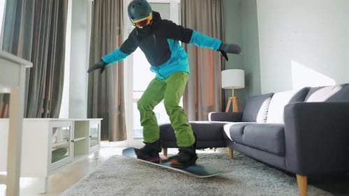 Fun Video. Man Dressed As a Snowboarder Rides a Snowboard on a Carpet in a Cozy Room. Waiting for a