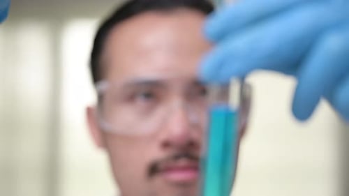 Lab scientist pouring liquid in lab flask. Close up of female scientist doing laboratory experiment