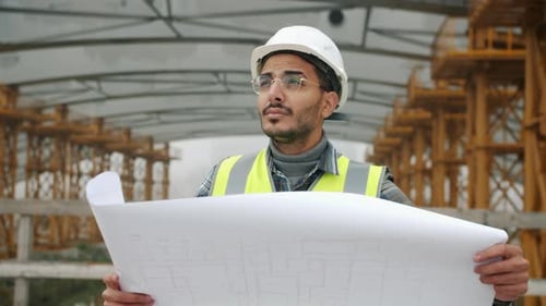 Engineer Inspects Blueprint at Construction Site