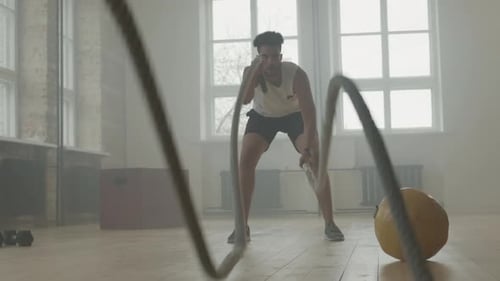 Strong Man With Battle Rope In Gym