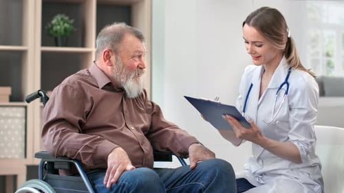 Doctor Talks to Senior Man in Wheelchair