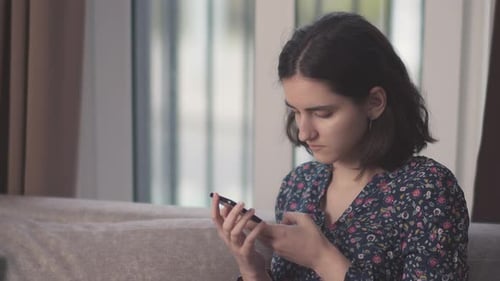 Young Woman Using Smartphone While Relaxing Indoors