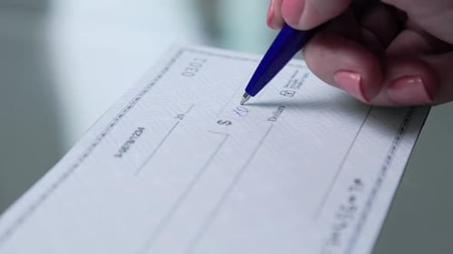 business woman hand signs and filling bank check for one thousand 1000 dollars
