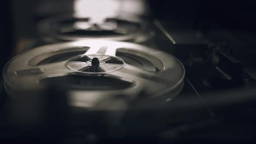 Vintage Reel-to-Reel Tape Recorder Spinning in Dim Light