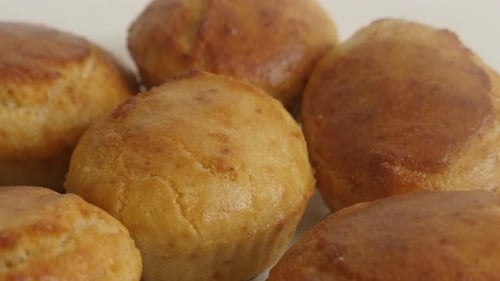 Tilting on cornmeal on white plate 4K 2160p 30fps UltraHD footage - Muffin shaped cornbread slow ti