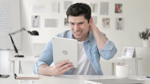 Man using tablet in bright office, feels pain